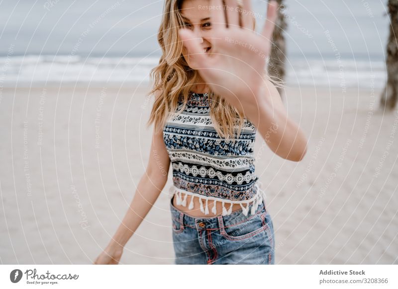 Happy female posing on sandy beach woman covering face hand happiness blocking face fashionable glamorous summer vacation holiday young person attractive