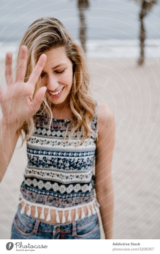 Happy female posing on sandy beach woman covering face hand happiness blocking face fashionable glamorous summer vacation holiday young person attractive