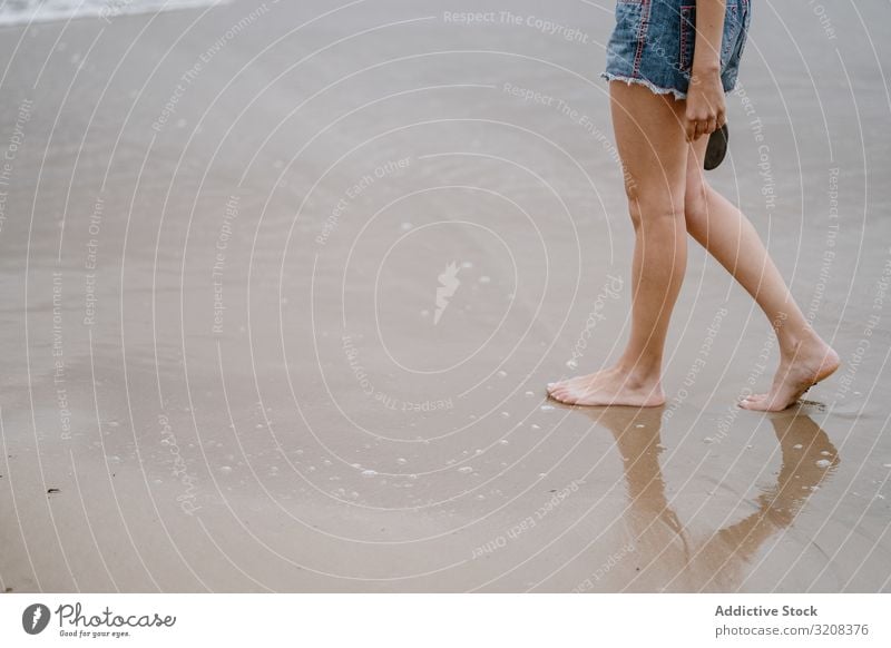 Young female walking barefoot on wet sand woman beach summer vacation travel recreation holiday joy freedom happiness young person attractive casual carefree