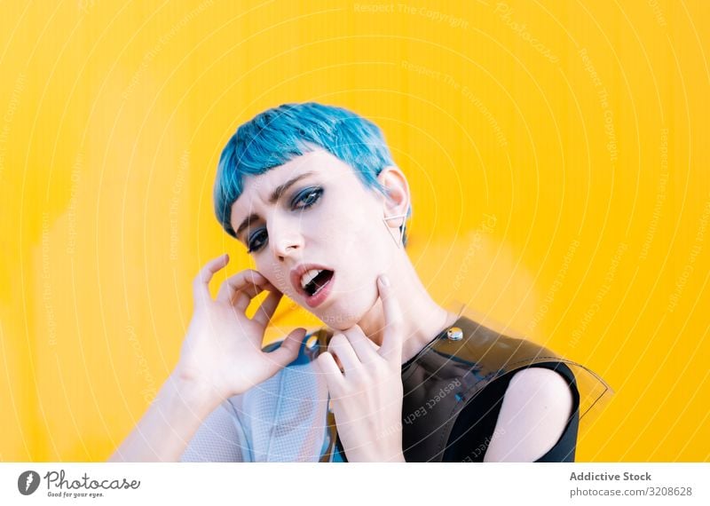 Alternative model portrait against yellow wall woman futuristic alternative dress blue hair informal pavement glamour lady young expression vogue female beauty