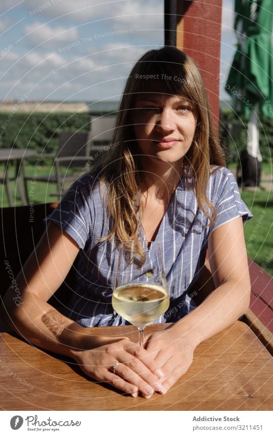 Young woman drinking wine in arbor resting chill vacation glass table sunny smiling countryside nida lithuania wooden young adult dress peaceful white daylight