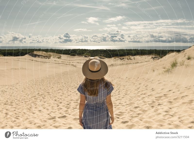 adult woman in casual dress and straw hat standing having good time on sand dune summer dreamy hot tourism modern clear sky scenic nida lithuania sunlight