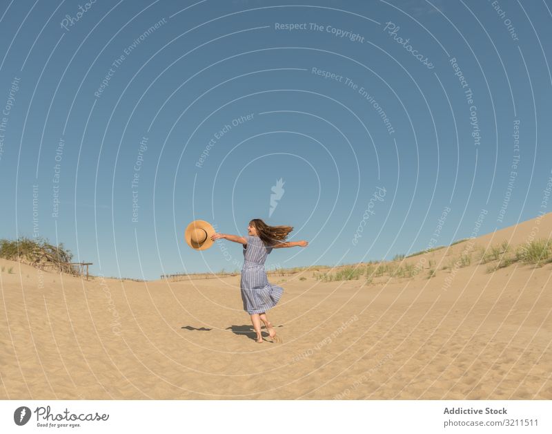 adult woman in casual dress and straw hat running having good time on sand dune summer dreamy hot tourism modern clear sky scenic nida lithuania sunlight sunhat