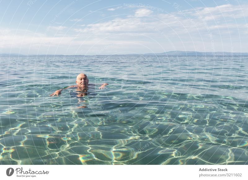 Mustached elderly man swimming in clear water sea retired vacation senior greece halkidiki ocean marine crystal leisure happy floating energy seashore summer