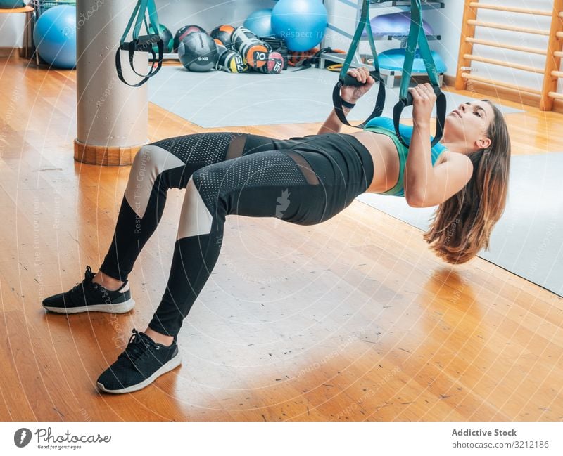 Young female training at the gym sportswoman suspension rope exercise trx bodyweight hanging physical athlete workout motivation strength power modern wellbeing