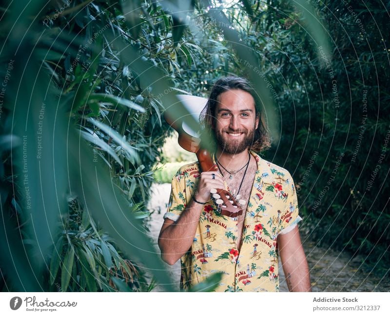 Hipster man in jungle with ukulele hipster musician travel adventure trip summer lifestyle pensive male vacation freedom young tourist colorful casual tropical