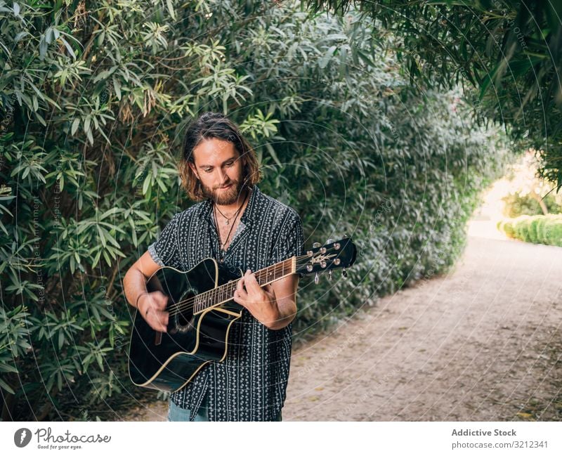 Hipster man in jungle with guitar hipster musician playing adventure trip summer lifestyle pensive male acoustic young entertainment leisure practice nature