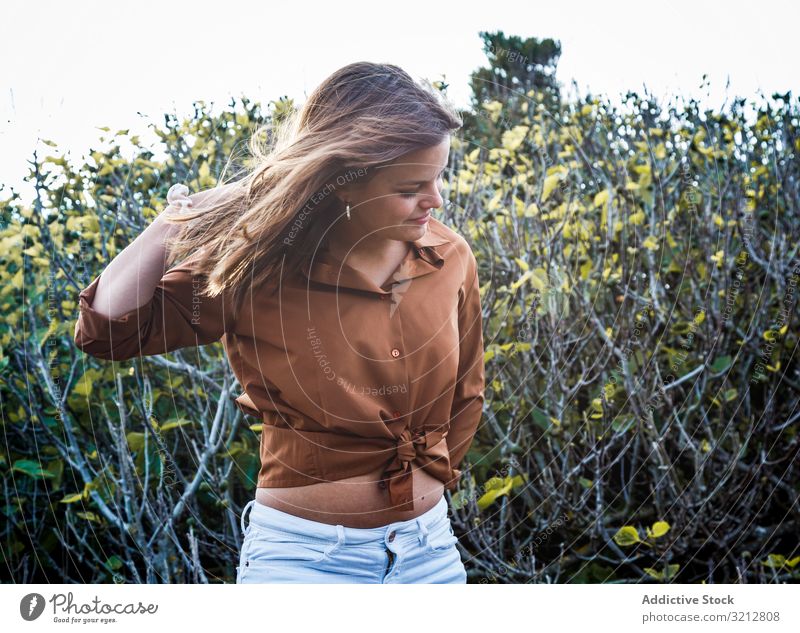 Happy woman standing in front of bushes nature cheerful summer happy carefree field country smiling beautiful attractive female hand on head enjoy freedom