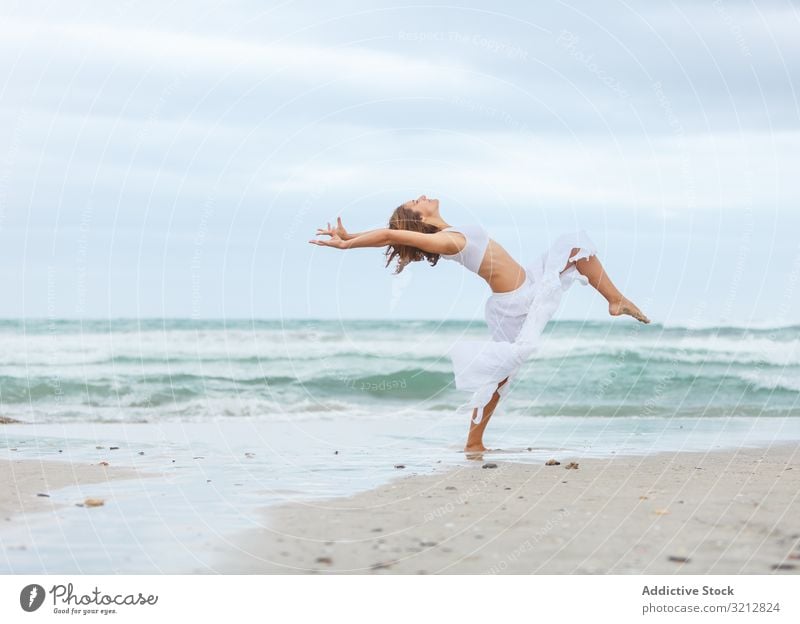 Beautiful woman dancing near sea sand shore freedom concept nature waves weather female movement posture white outfit coast beach ocean water carefree lady