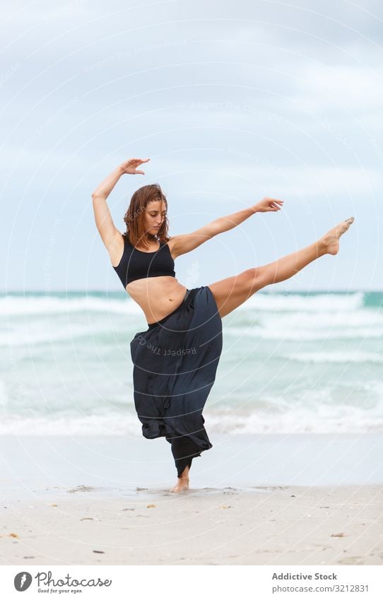 Beautiful woman dancing near sea sand shore freedom concept nature waves weather female movement posture black outfit coast beach ocean water carefree lady