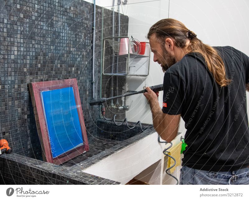 Artist preparing silkscreen for serigraphy artist workshop printing prepare creating man blue hobby easel paint drawing male concentration focused occupation