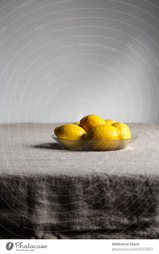 Ripe juicy lemons in plate on table citrus food fresh ripe glass grey linen yellow sour shiny raw organic natural peel tablecloth freshness vegetarian