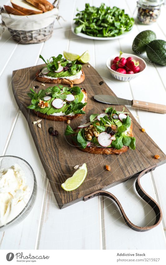 Vegetarian sandwiches on cutting board toasts vegetables radish herbs avocado lime healthy diet vegan vegetarian rustic snack breakfast bread food portion meal