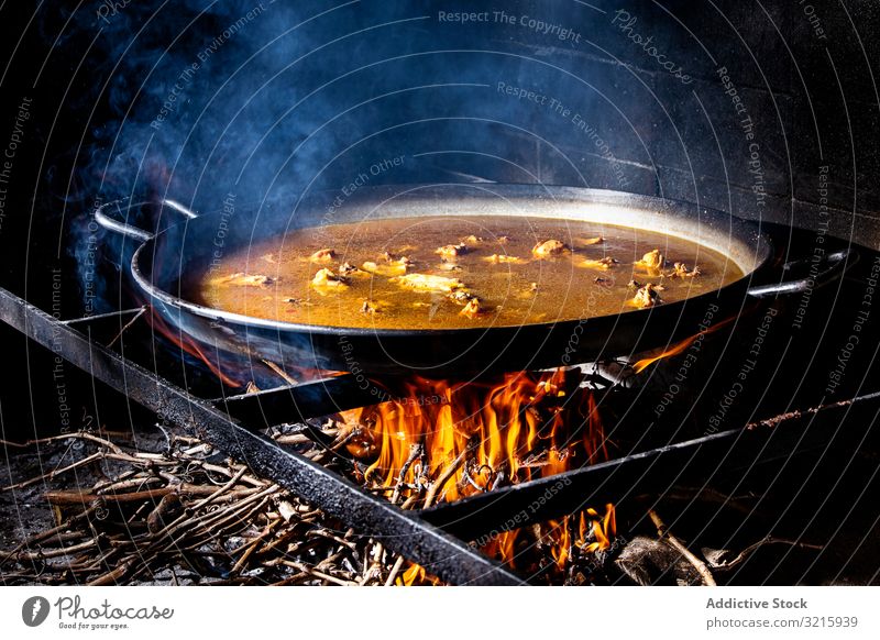 Process of cooking paella on fire rice process cuisine adding spanish traditional food chicken broth flame iron big wood heat hot brick stove dinner seafood