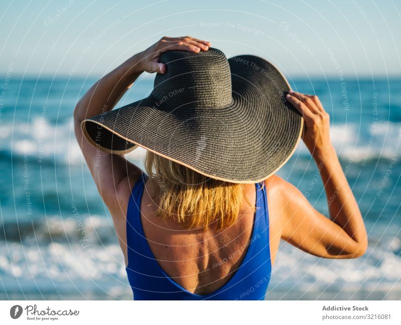 Woman in blue swimsuit and hat on sandy beach woman slim foam swimwear wave water summer leisure tanned attractive seaside covered female turquoise lifestyle