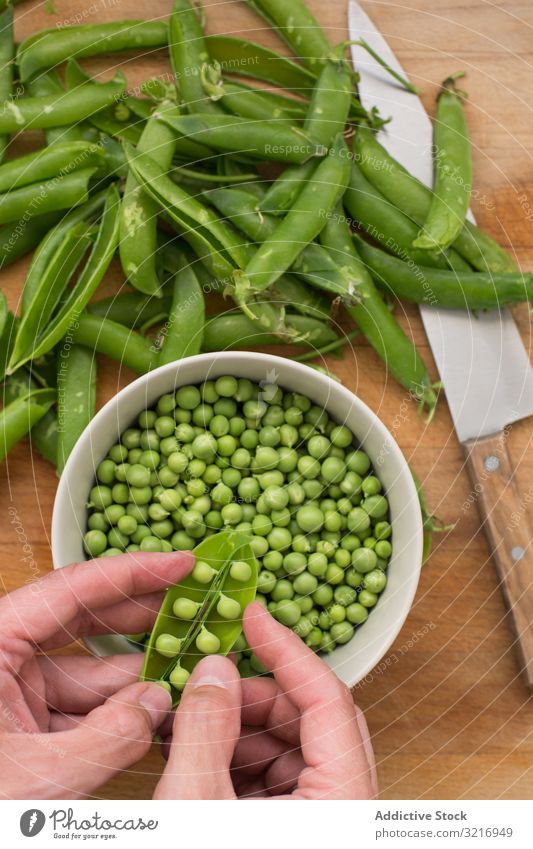 Peeling pea pods bowl ecological food fresh green hand healthy legume natural opening organic raw seed vegetable vegetarian wooden summer hands vegan