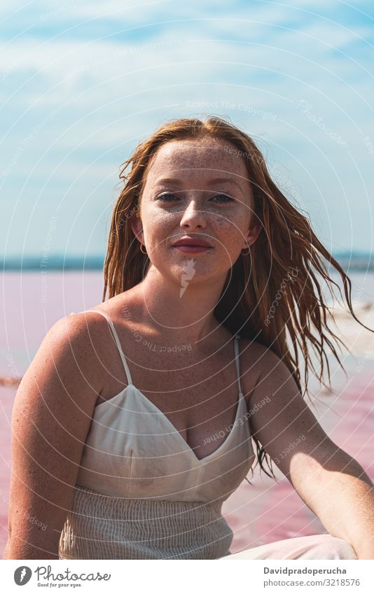 cute teenager woman wearing white dress sitting on an amazing pink lake young saline summer freckles happy alone sea colorful nature water copy space paradise