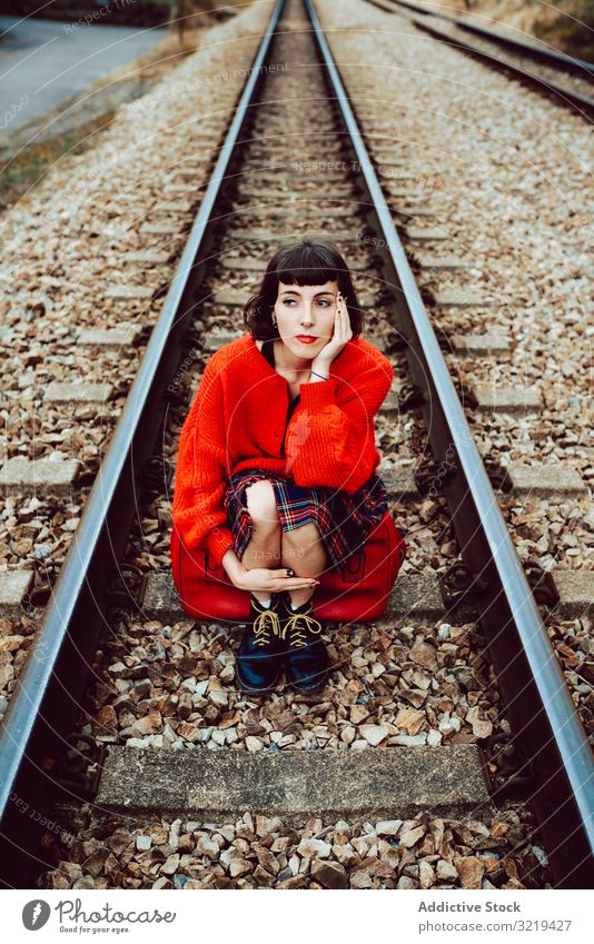 Woman sitting on sleepers in middle of railway woman railroad suitcase red travel stylish green female luggage nature beautiful bag waiting freedom alone trip