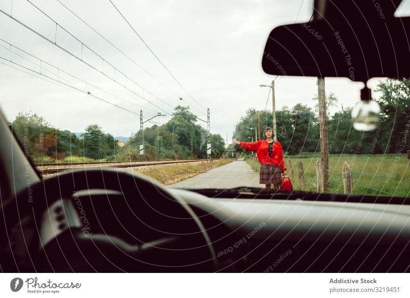 Woman in red sweater catching car on road woman auto stop suitcase gesturing travel stylish female hitchhiking luggage nature beautiful bag fashion waiting