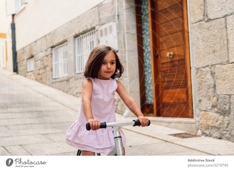 Girl riding on bicycle in narrow street smiling bike summer girl happy fun sport city cheerful day active childhood urban cyclist holiday lifestyle joyful dress