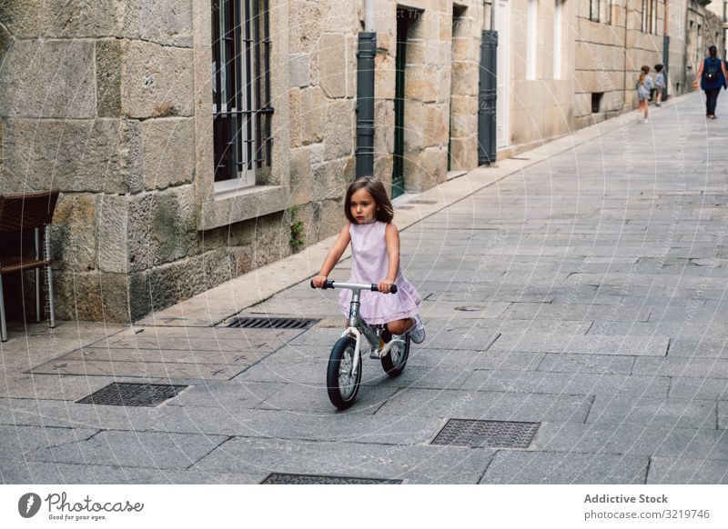 Girl riding on bicycle in narrow street smiling bike summer girl happy fun sport city cheerful day active childhood urban cyclist holiday lifestyle joyful dress