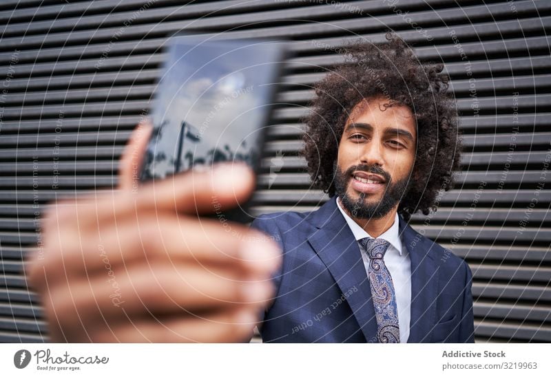 Joyful ethnic man taking selfie and smiling modern businessman formal african black smartphone wall smile happy afro cheerful african american office suit curly