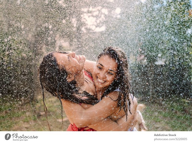 Friends in swimsuits hugging under water drops women splash garden friend girlfriend holiday fall summer hose fun cheerful joy friendship bonding together