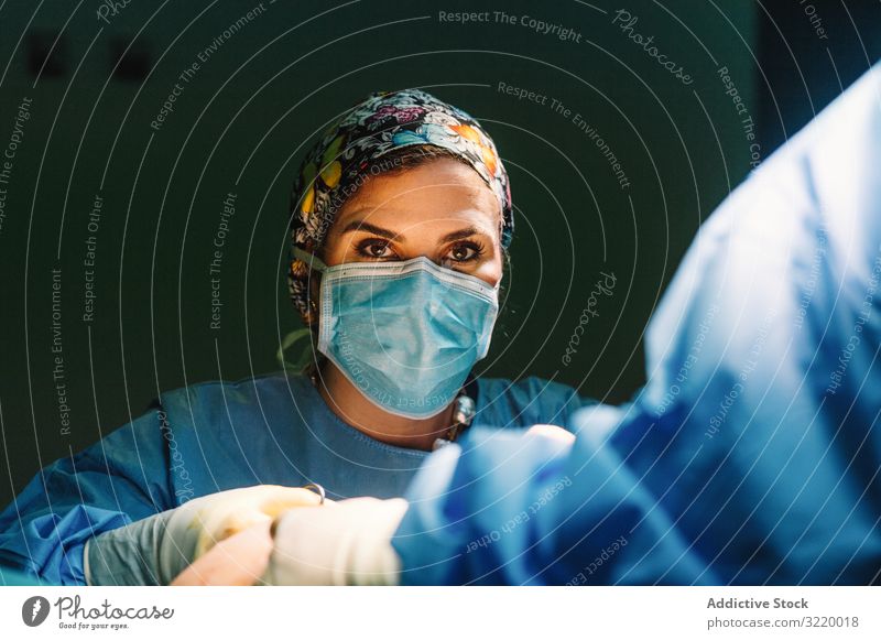 Concentrated female surgeon at work woman doctor surgery hospital operation medicine profession concentration young serious attentive surgical gown blue cap