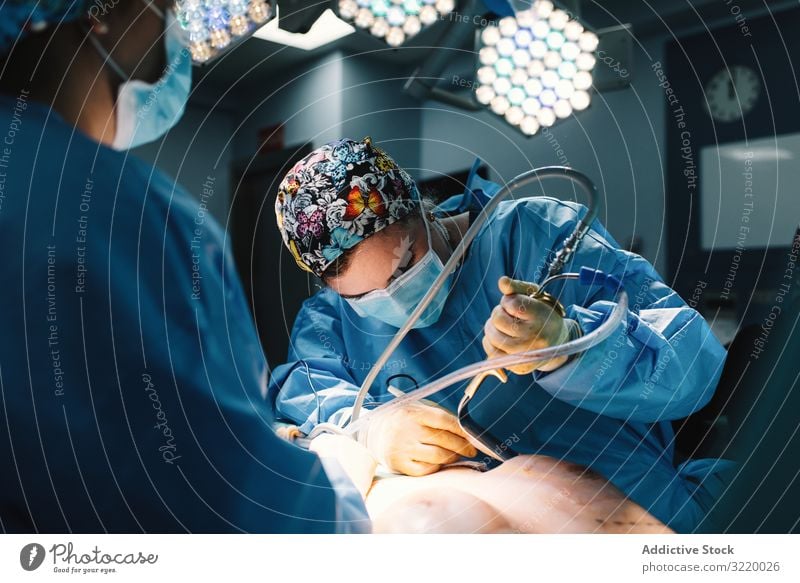 Concentrated female surgeon at work woman doctor surgery hospital operation medicine profession concentration young serious attentive surgical gown blue cap