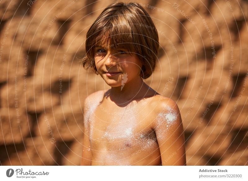 Boy with sunscreen on the body looking at the camera kid cream sunblock boy summer beach protection vacation care help childhood family apply suntan leisure