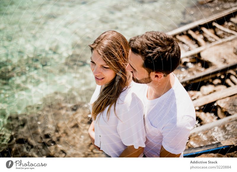 Happy lovers cuddling at cove Formentera balearic islands Spain couple bay summer rest cuddle embrace happy joyful sensual shirt white sea vacation leisure