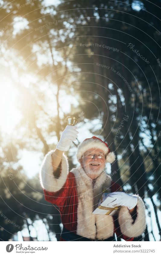 Santa Claus with gift and bell santa claus man holiday christmas present celebration event senior male pensive thoughtful serious bearded gray-haired