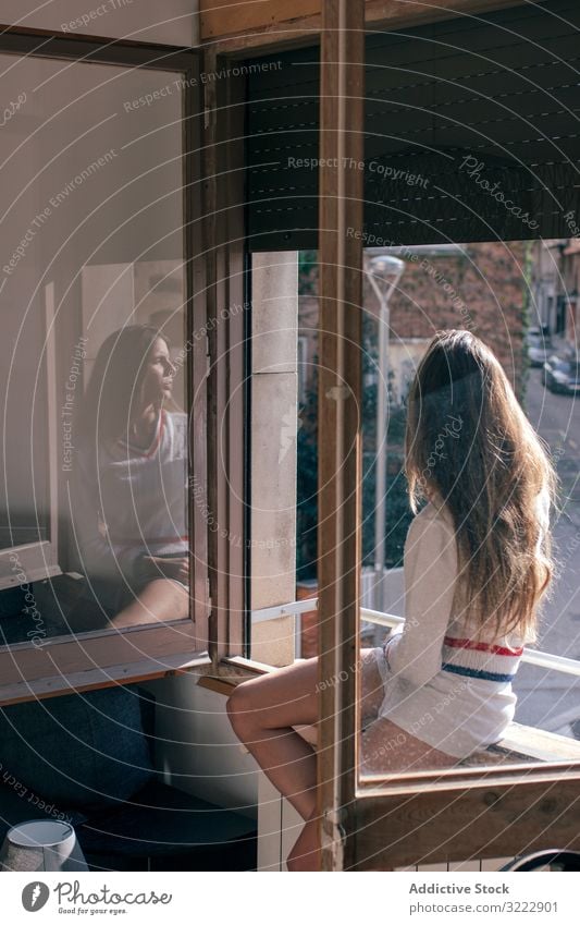 Woman sitting on window sill woman pensive tender thoughtful home calm sensual attractive female apartment casual young beautiful pretty upset morning relax