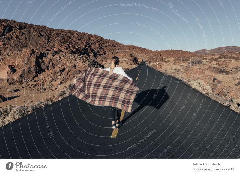 Woman with plaid walking on empty road woman freedom tenerife dreamer carefree waving run traveler trip blanket wind desert mountain hills spain road trip