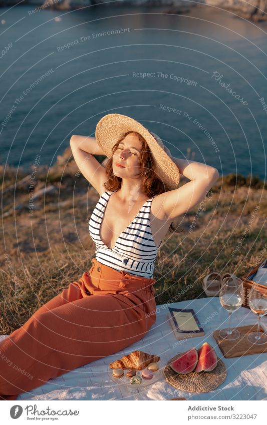 Woman resting in meadow on picnic woman summer leisure relax glass drink vacation summertime vintage fashion refreshing watermelon beautiful serenity hat