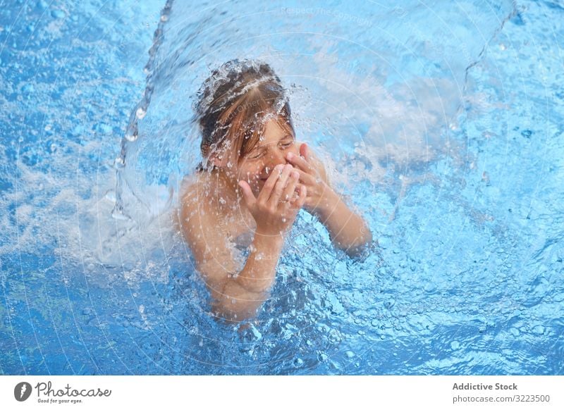 Young boy in blue water swimming pool young child float gasp for air closed eyes open mouth waterfall waterpark activity fun joy health leisure lifestyle