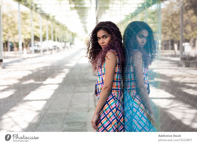 Sensual ethnic woman on street near glass wall Adriana woman brazilian urban sensual reflection lean beautiful colorful embrace curly young purple attractive