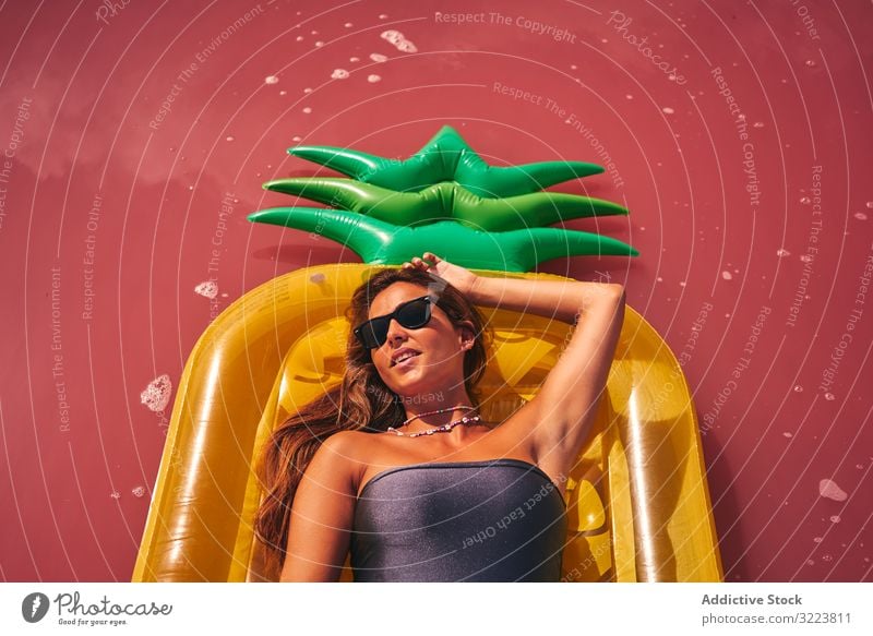 Dreamy female resting on inflatable mattress woman chill lying summer air mattress dreamy pink luxury appealing sunglasses swimwear red lagoon vivid creative