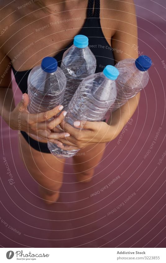 Concerned female in swimsuit collecting trash in natural lake pollution water contamination woman concerned pool pick bottle plastic red lagoon planet safety