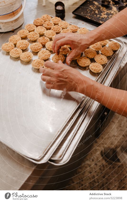 Crop baker arranging patisserie on tray confectioner bakery pastry arrange work cook quality food traditional preparation small business occupation busy job set