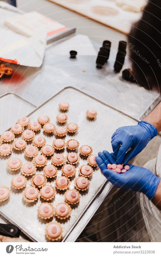 Anonymous baker decorating small cakes confectioner bakery pastry work quality food traditional man preparation production small business occupation patisserie