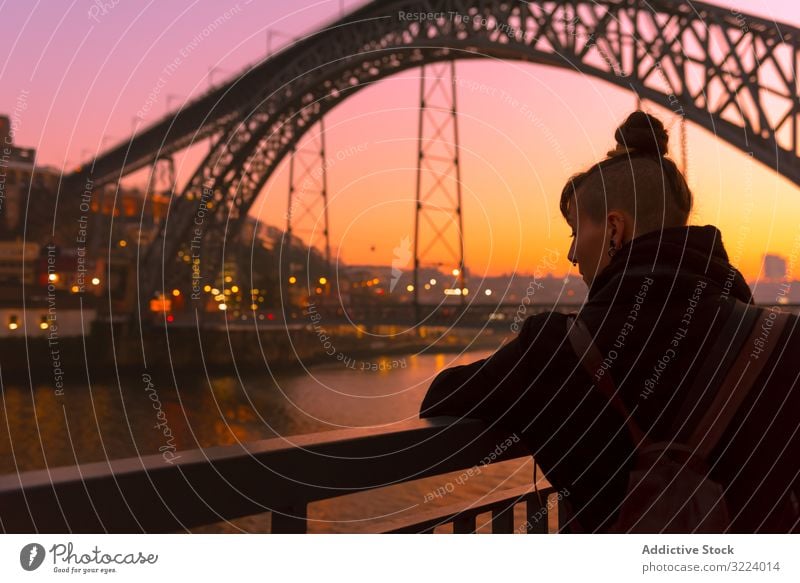 Female standing on embankment during sundown tourist city sunset bridge river sit border woman water architecture landmark sky cloudless female evening dusk