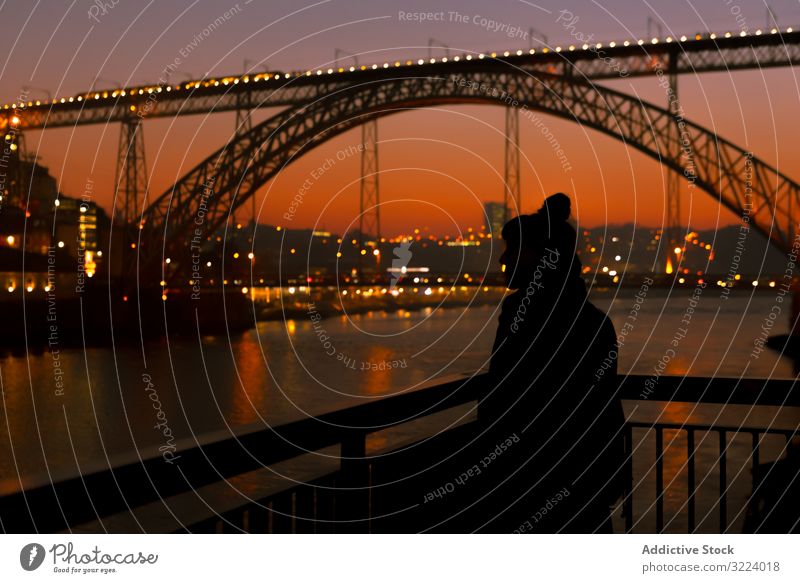 Female walking on embankment during sundown tourist city sunset bridge river border woman water architecture landmark sky cloudless female evening dusk twilight