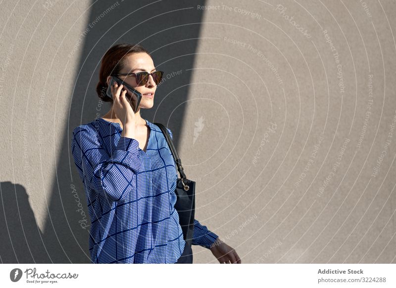 Businesswoman having smartphone conversation near gray wall businesswoman street talk building modern city urban female communication work job mobile device