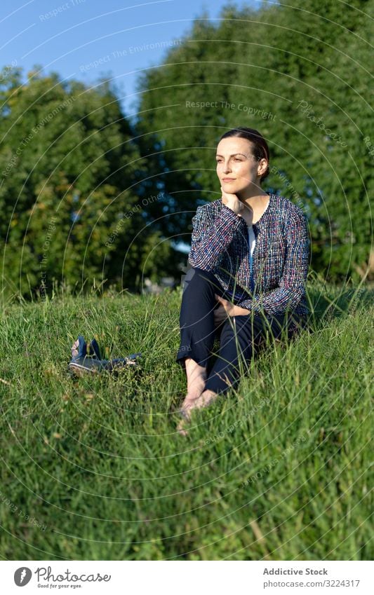 Female manager resting in park businesswoman lawn sit touching neck barefoot green grass bush female entrepreneur break relax harmony idyllic dreamy thoughtful