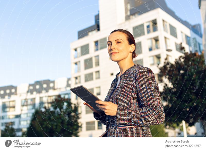 Confident entrepreneur with tablet on city street businesswoman using building serious confident sunny daytime female urban work job internet device gadget lady