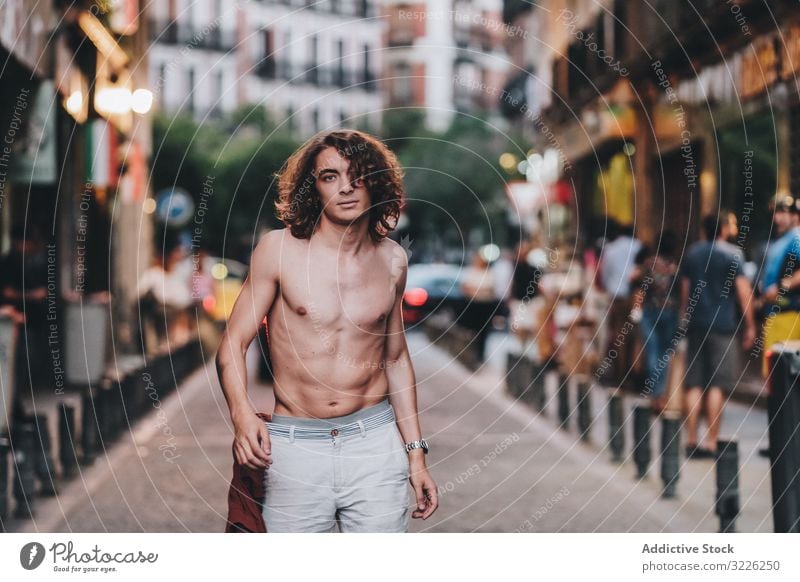 Sensual man gazing and standing shirtless on street sensual gaze confident pensive naked handsome urban long hair young adult day desire passion sexual body