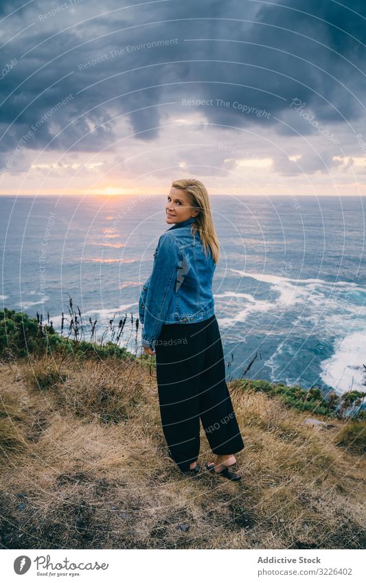 Woman on seashore against dusky clouds woman horizon seascape sunset harmony contemplation overcast chill scenic trip travel ocean tranquil recreation twilight