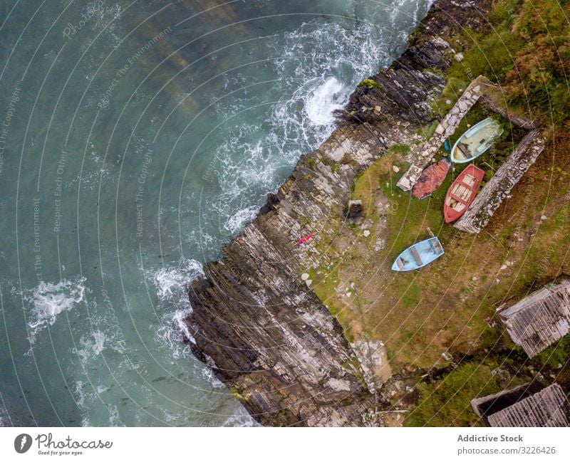 Boats on small part of seashore washing by foamy waves boat seaside water ocean coast vacation nature travel scenery green peak yacht sailboat bay scenic