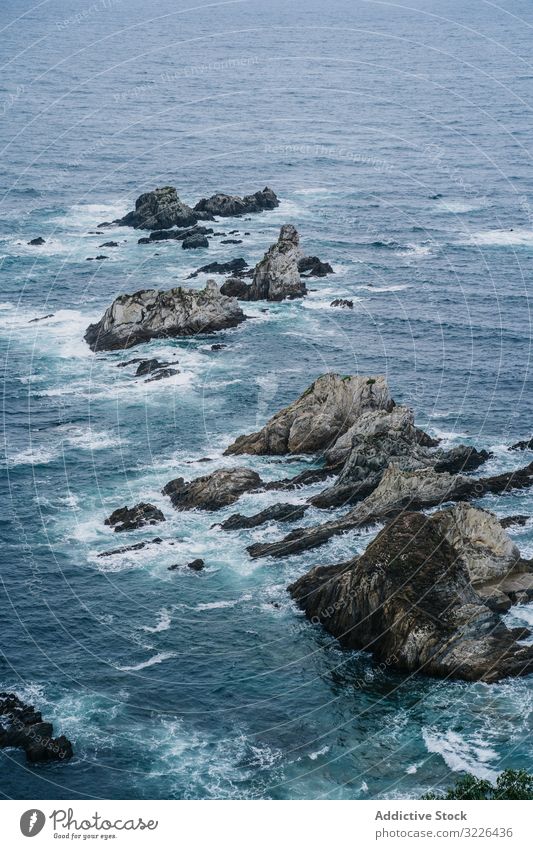 Rocky peaks surrounded by foamy water in windy day ocean scenic cloud nature landscape nautical dramatic rocky sea coast travel tourism natural dangerous